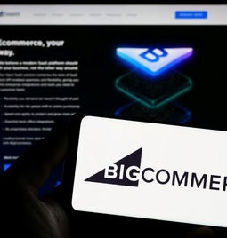 Photo of a laptop screen and phone in front with the BigCommerce logo on the screen