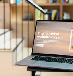 Laptop on a desk showing Squarespace's homepage with the text 'The leader in website design'.