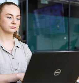 A focused professional woman works intently on her laptop in her business' office