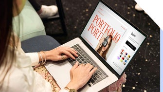 Woman working on her portfolio website design on her laptop in a casual setting.