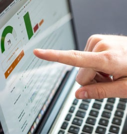 Photo of a hand pointing to a laptop screen with SEO metrics