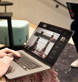 Two professionals working on laptops in a modern office setting, one is editing her website on GoDaddy's website builder.