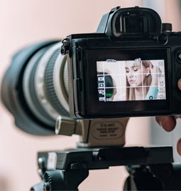 Hand holding lens camrera with a person visible through the preview screen