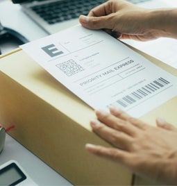 Person placing a shipping label onto a package