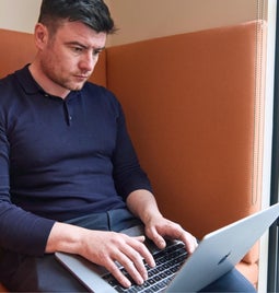 Man concentrates working and typing on his laptop in a modern office setting