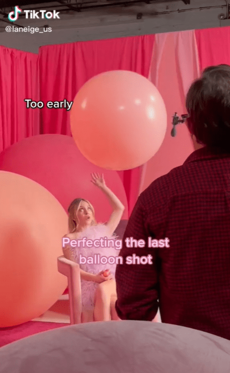 Model sits surrounded by pink balloons during photoshoot