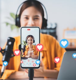 girl vlogging for social media on phone with graphic hearts