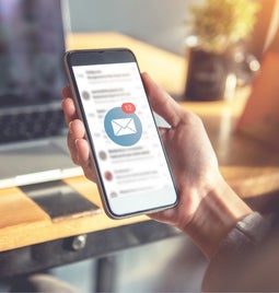 person holding phone with email inbox open