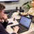 Man looks thoughtfully at the Google search on his laptop screen, as part of a business meeting with colleagues in an office.