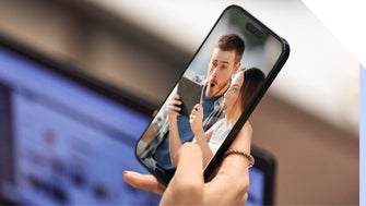 Hand holding smartphone, with an image of a comically surprised-looking couple on the screen.