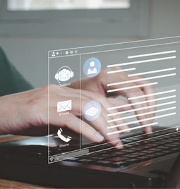 Person typing on laptop with a hologram of a messaging platform above the keyboard