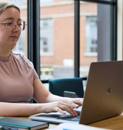 A focused professional woman working diligently on a laptop in an office setting