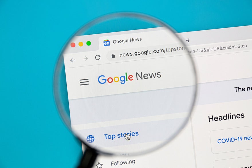 A magnifying glass zooming into the Google news webpage