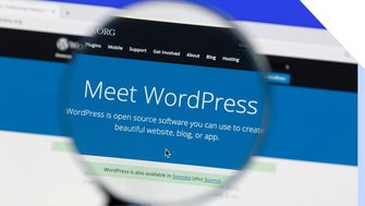 Magnifying glass held over screen showing WordPress homepage